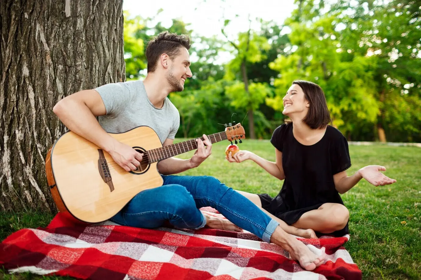 Ein junges, schönes Paar lächelt und entspannt sich bei einem Picknick im Park.